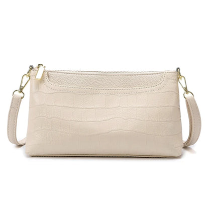 Beige leather bag with crocodile texture, with removable strap and zipper closure - front view.