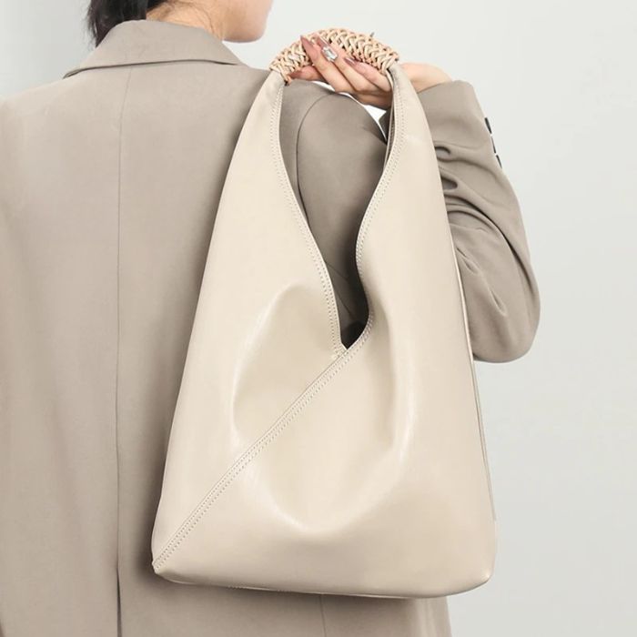 A woman carrying a modern white leather bag, with a minimalist design.