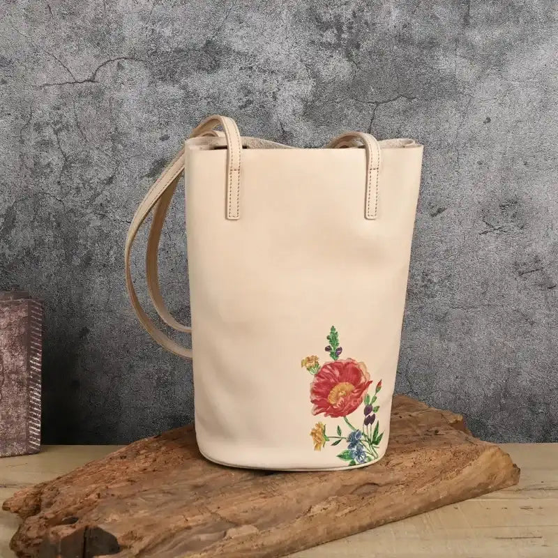 Beige leather tote bag with colorful floral print on a natural background, front view.