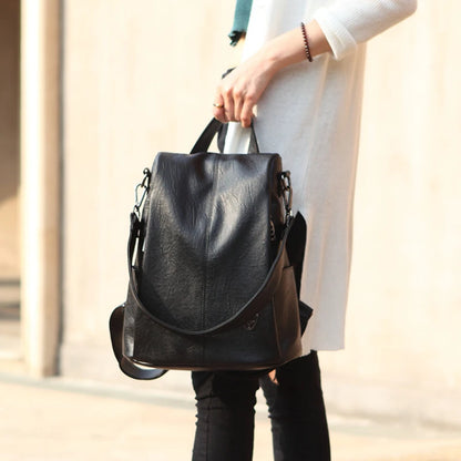 A stylish black anti-theft leather backpack carried by a woman in a casual outfit.