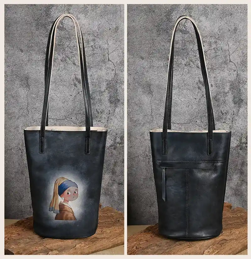 Black leather tote bag with artistic design print, with leather handles and back zipped pocket, front and back views.