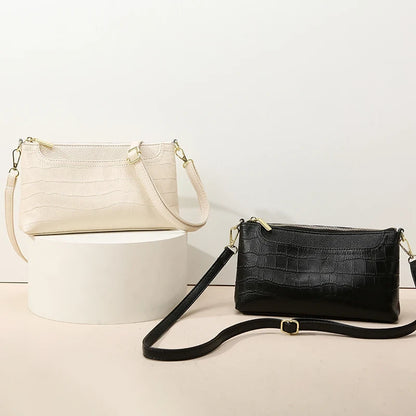 Two elegant leather bags, one in beige and one in black, sdisplayed against a light surface.