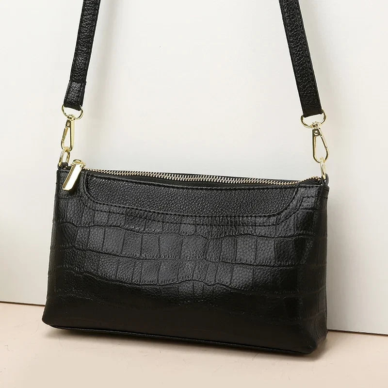 Elegant black leather bag with crocodile texture and adjustable strap creating sophisticated and modern look.