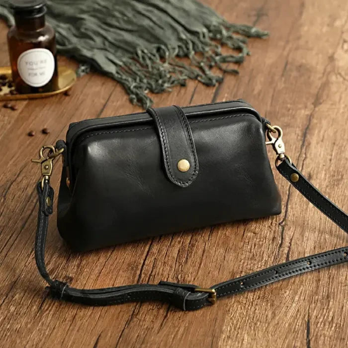 Black leather shoulder bag with leather adjustable strap and snap closure, front view.