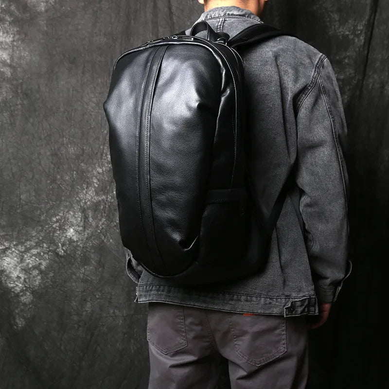 A man wearing a black leather backpack, highlighting the modern and minimalist style of the piece. 