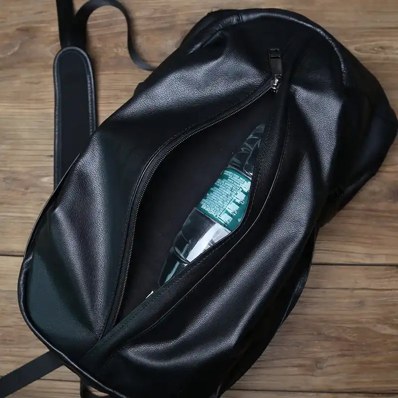 Black leather backpack with an open zipper, revealing a water bottle inside.