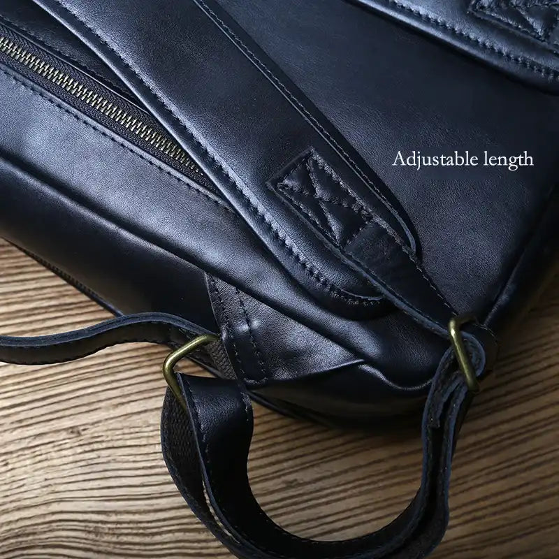 Close-up of a black leather backpack showcasing its adjustable strap and zipper.