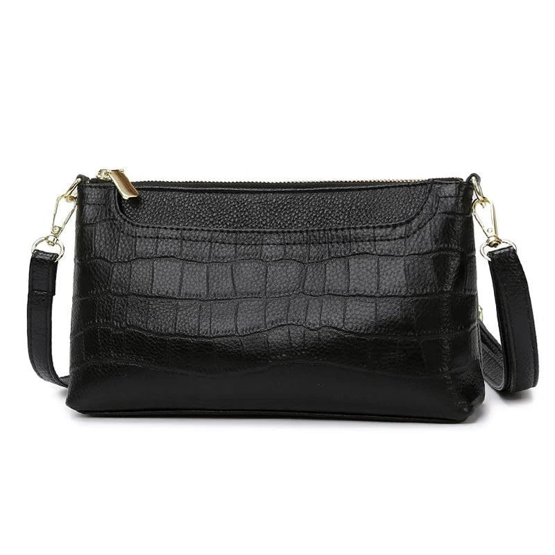 Black leather bag with crocodile texture, with removable strap and zipper closure - front view.