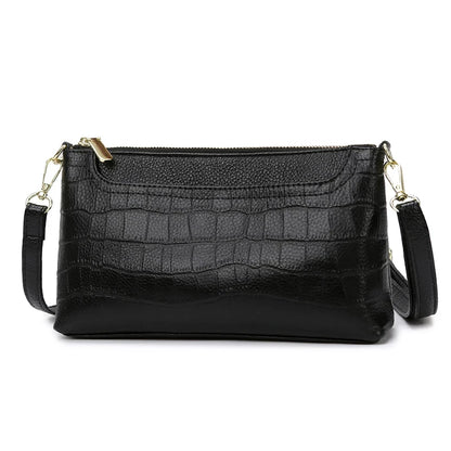 Black leather bag with crocodile texture, with removable strap and zipper closure - front view.