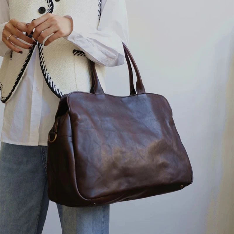 A stylish woman holding a black leather bag on elbow.