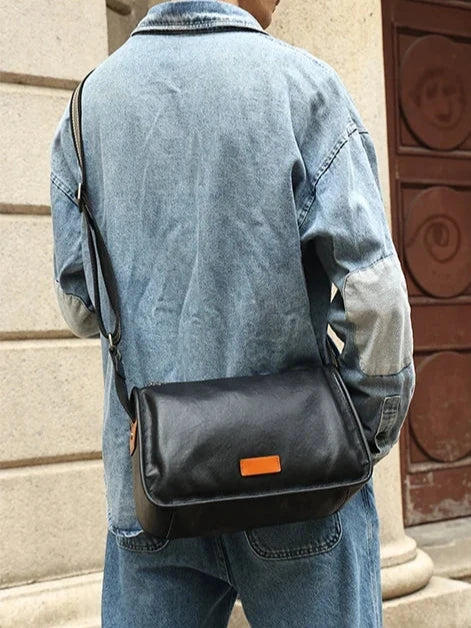 man wearing a denim jacket and a black leather bag across the body in a casual and modern look.