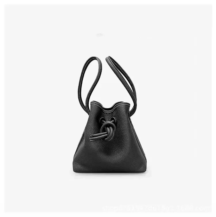 A stylish black leather bag with a unique knot design and dual handles - front view.