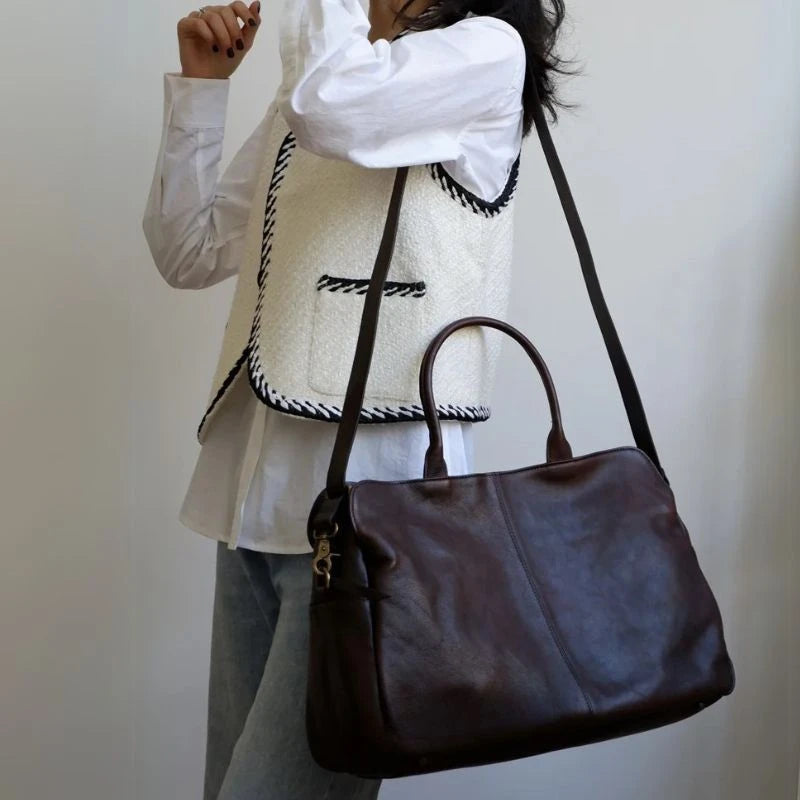 A stylish woman holding a black leather bag on shoulder.