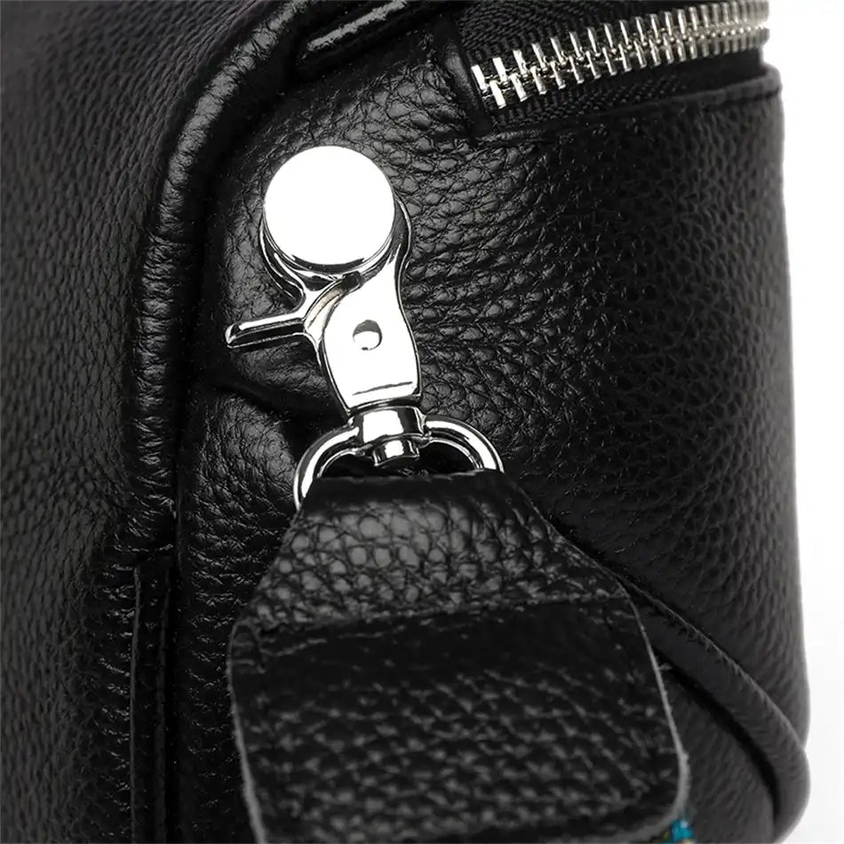Detail of a silver strap clip on a black leather bag, highlighting the quality and modern design of the accessory.