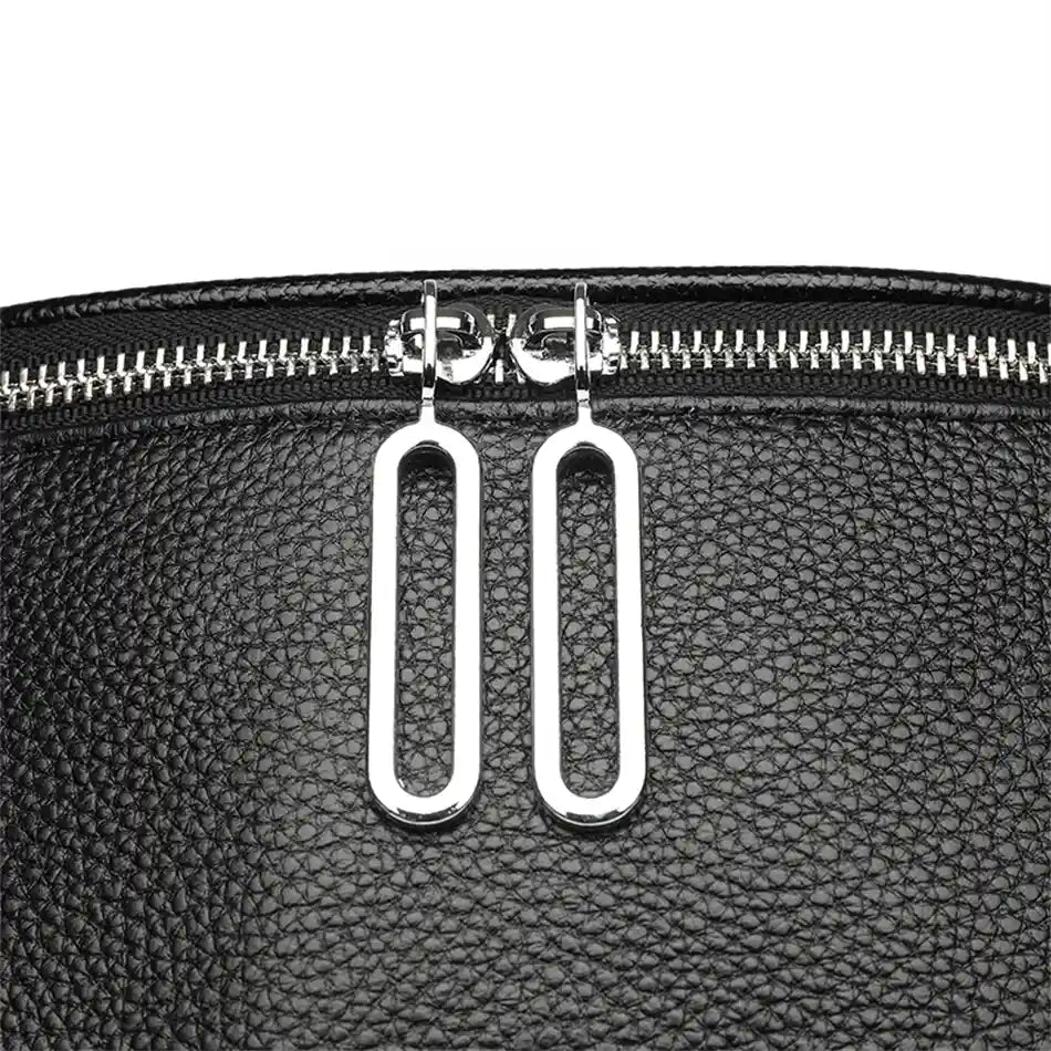 Detail of metal zippers on a textured black bag, showing the elegant design and the sophistication of the accessory.
