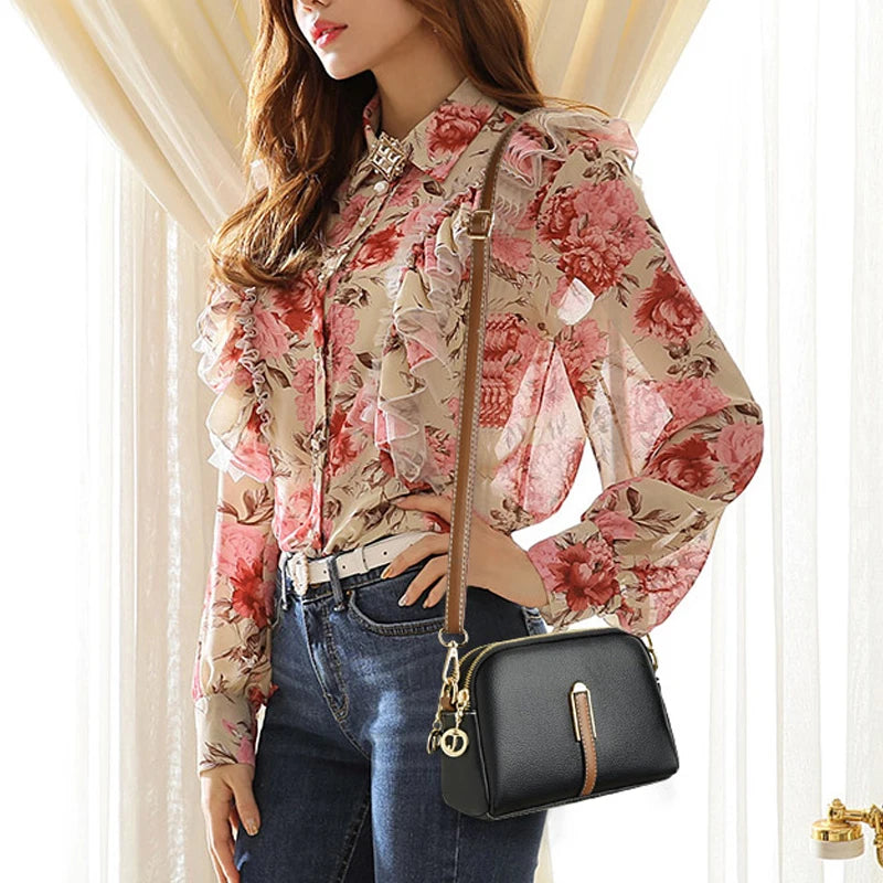 A fashionable woman in a floral shirt wearing a black leather crossbody bag.