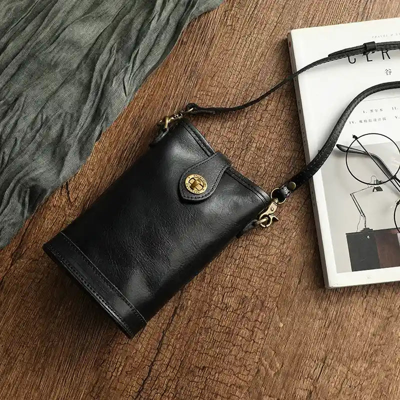 Chic black leather crossbody bag with gold accents on a rustic background.