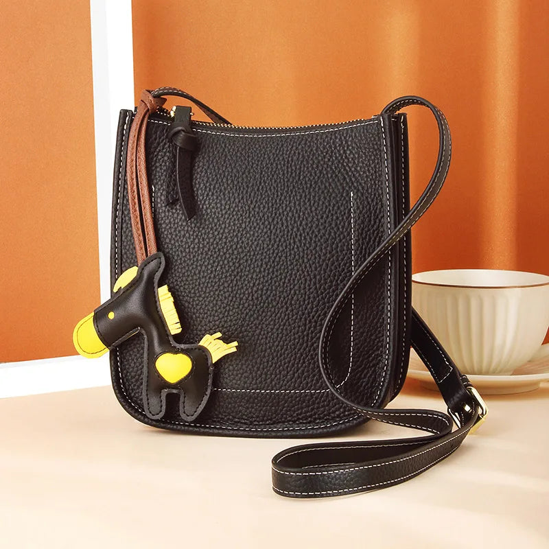 Front view of a stylish black leather crossbody bag featuring a cute horse charm