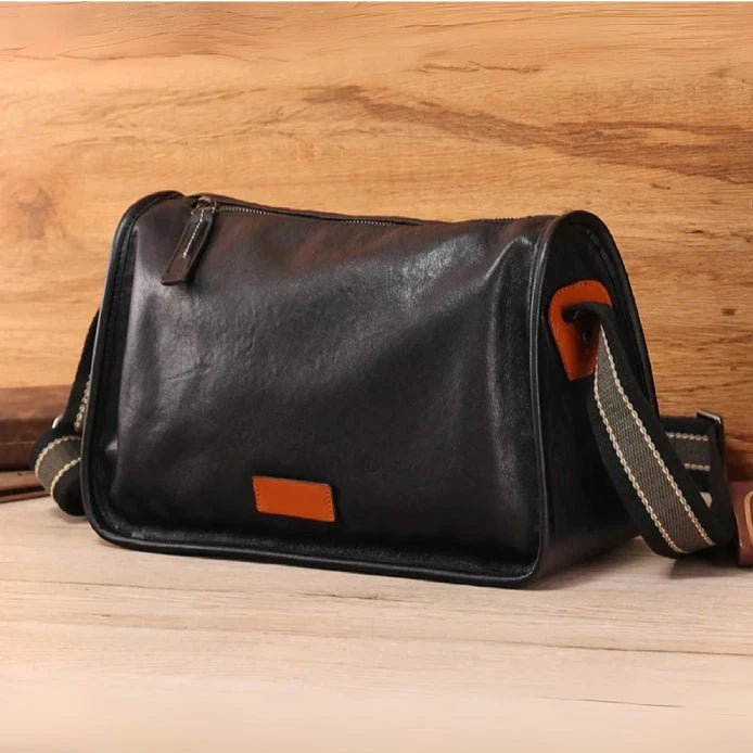 black leather shoulder bag with adjustable strap, front view.