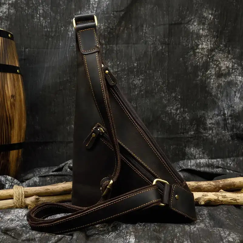 Stylish black leather sling bag with multiple zippers - back view.