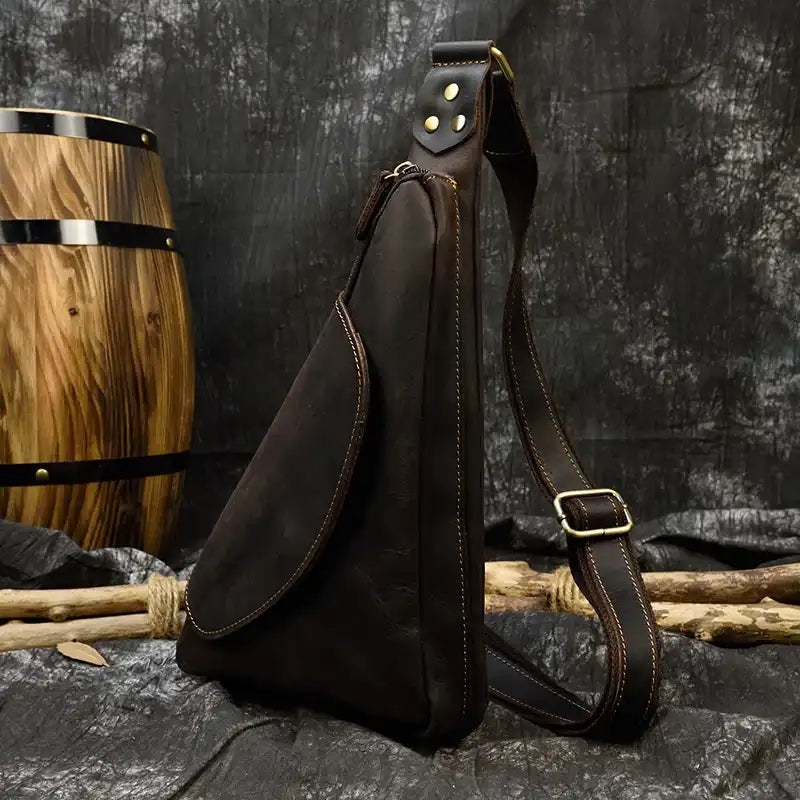 Elegant black leather sling bag with a unique design and detailed stitching.