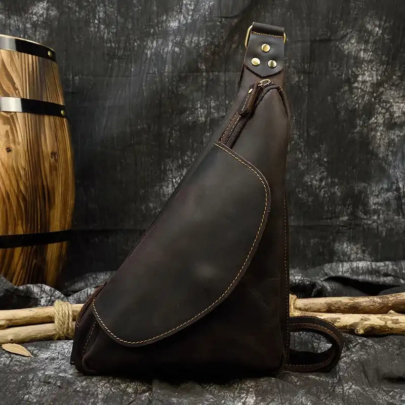 front view of a stylish leather sling bag with a unique triangular design.