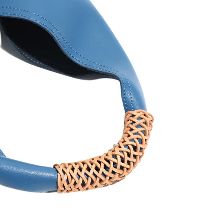 Close-up view of a blue leather bag with beige braided detail on handle.