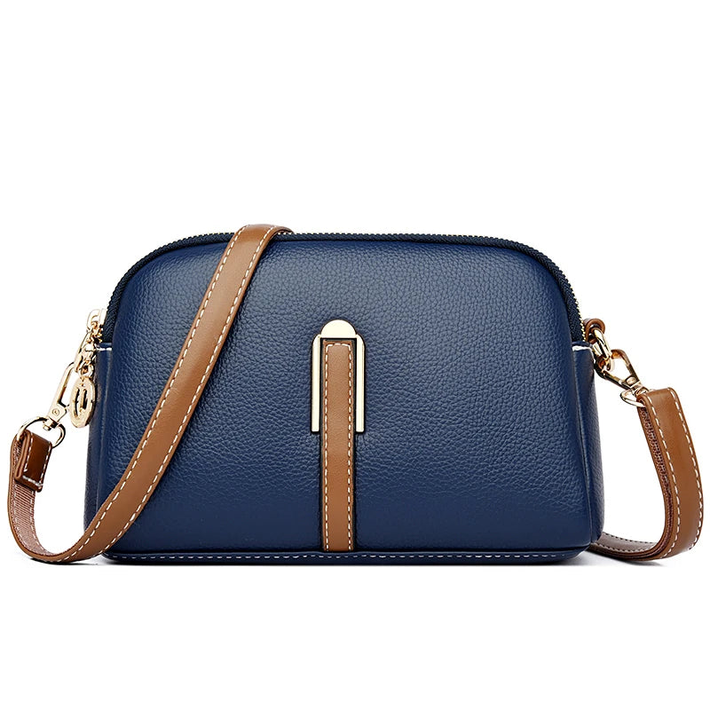 Chic blue leather crossbody bag featuring a gold accent and a brown strap - front view.