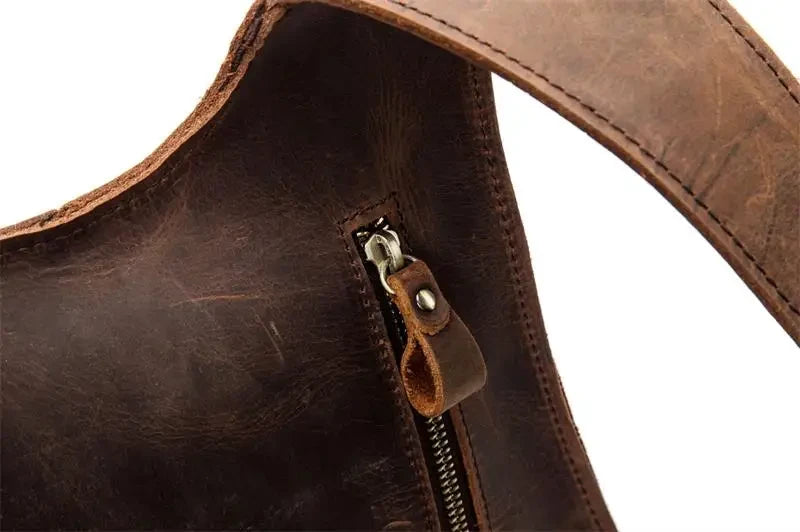 Detail of a brown leather bag, highlighting the zipper and handle details.