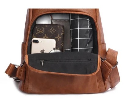 Organized storage space inside a leather backpack with various items.
