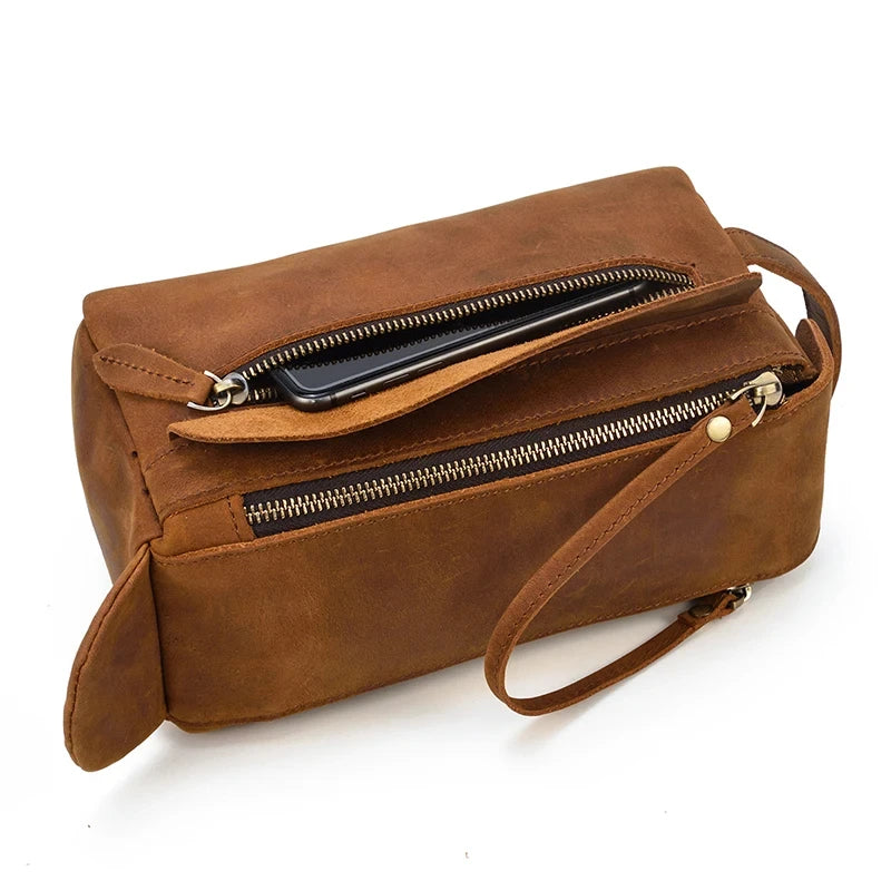 Close-up of a zippered brown leather clutch showcasing a smartphone in a side pocket.