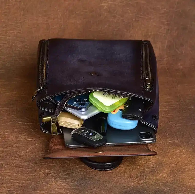 A dark brown leather bag filled with various items, including electronics, keys and accessories. Ideal for organization.