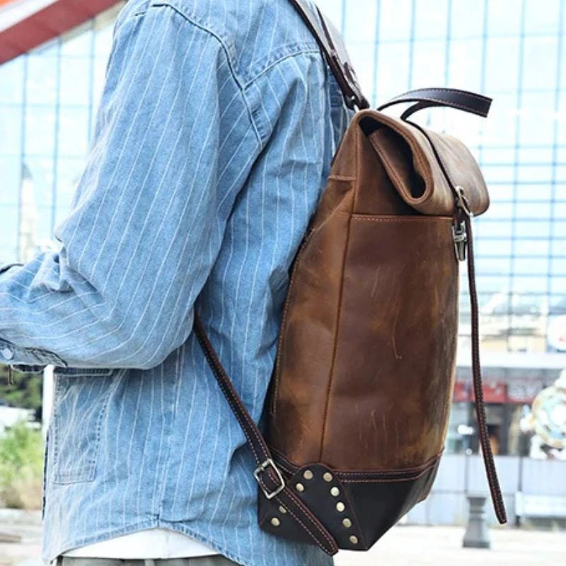 Elegant brown leather backpack worn by a man in a casual style.