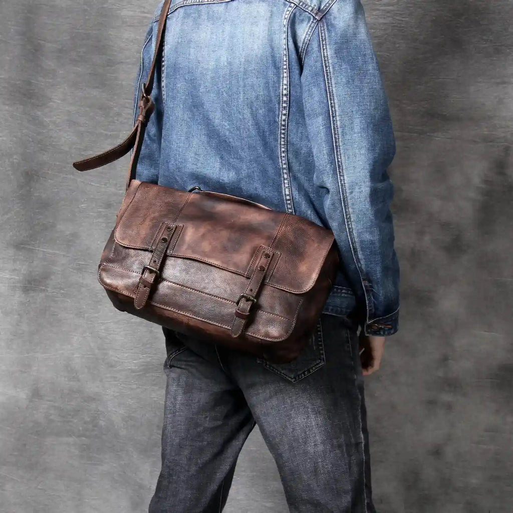 back view of a person wearing a denim jacket and holding a brown leather bag over the shoulder.