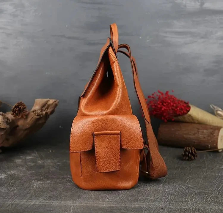 side view of a brown leather bag with a modern design, with adjustable strap and side pocket.
