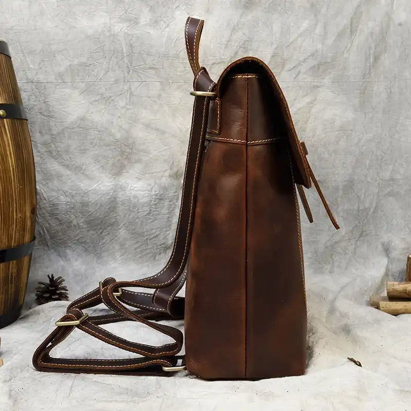 A stylish brown leather backpack, with a modern design and adjustable straps, side view.