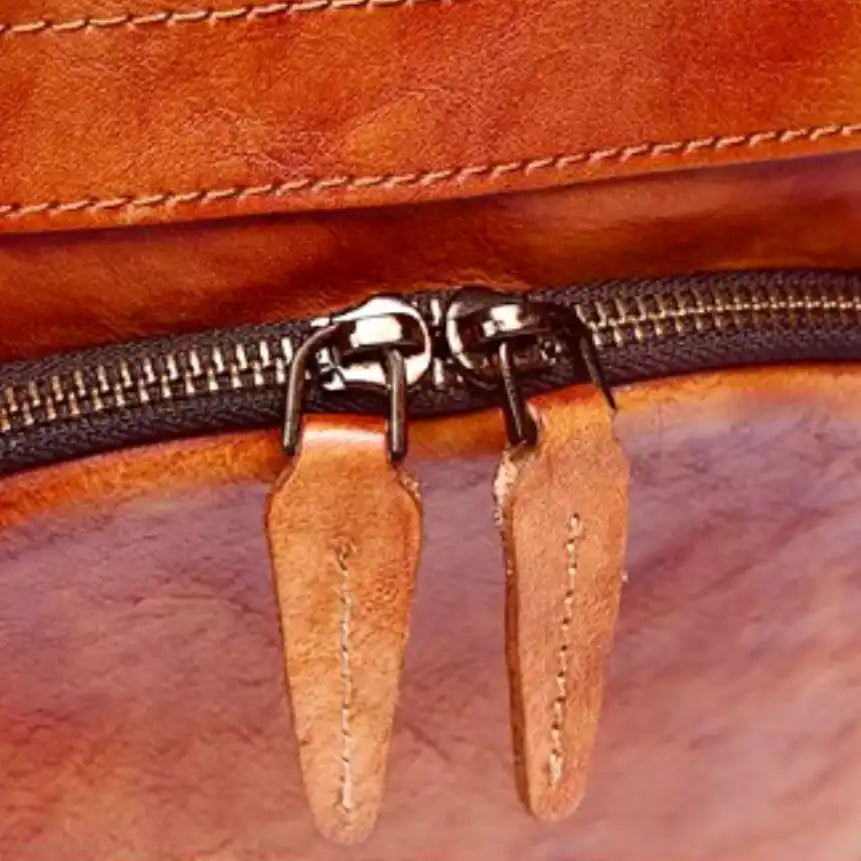 Detail of a zipper on a leather bag, highlighting the genuine leather finish and sophisticated design. 