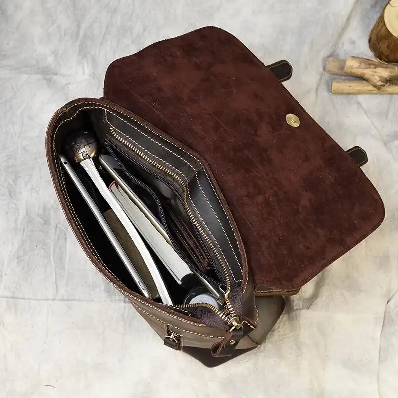 open brown leather bag with several items organized inside, showcasing large capacity.