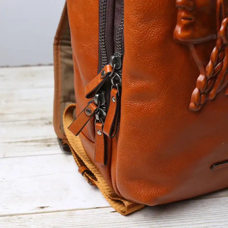 Detail of a zipper on a brown leather backpack, highlighting the texture and finishes of the material used.