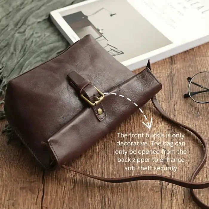 top view of a brown leather crossbody bag with decorative front buckle.