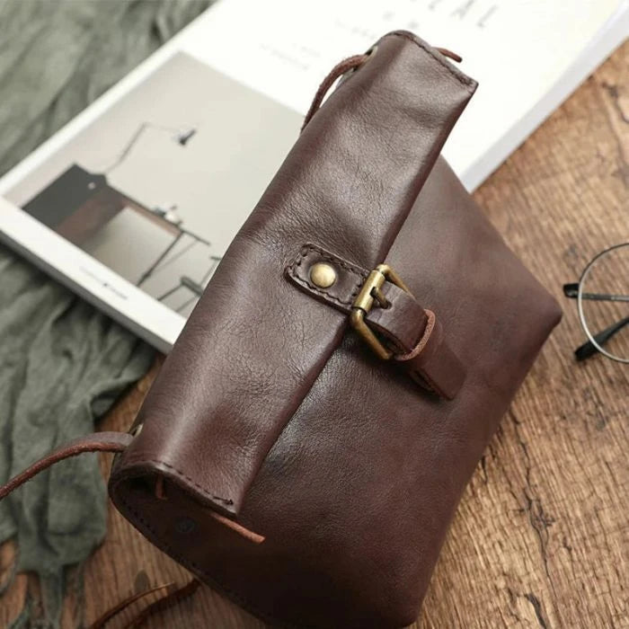 Brown leather crossbody bag with elegant buckle, side view.