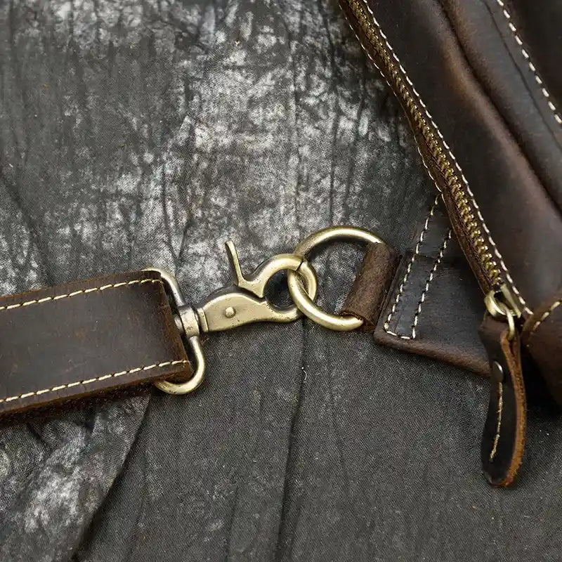 Metal clasp detail on leather bag, showing off the rich texture and highlighted stitching. 