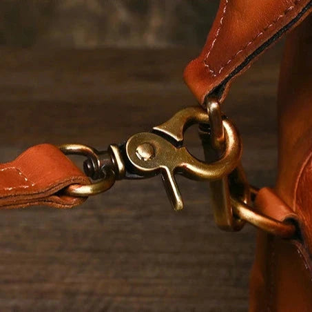 Detail of a metal clasp on a leather bag handle, highlighting the quality of the material and design.