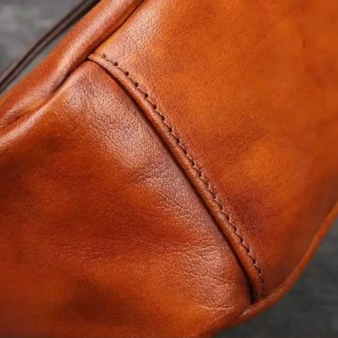 Detail of a high quality brown leather, showing the texture and finish of the stitching on a leather bag. 