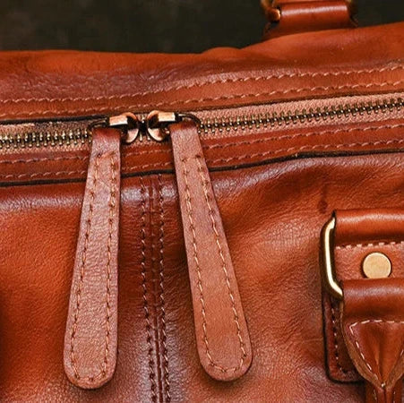 Detailed image of a brown leather bag, showing the zipper and finishing details.
