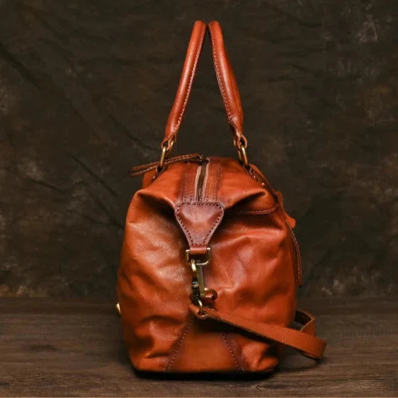 Vintage style brown leather bag with handles and zipper compartment, side view. 
