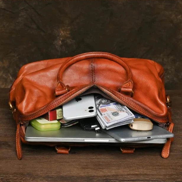 Open leather bag displaying a laptop, phones, and cash inside.
