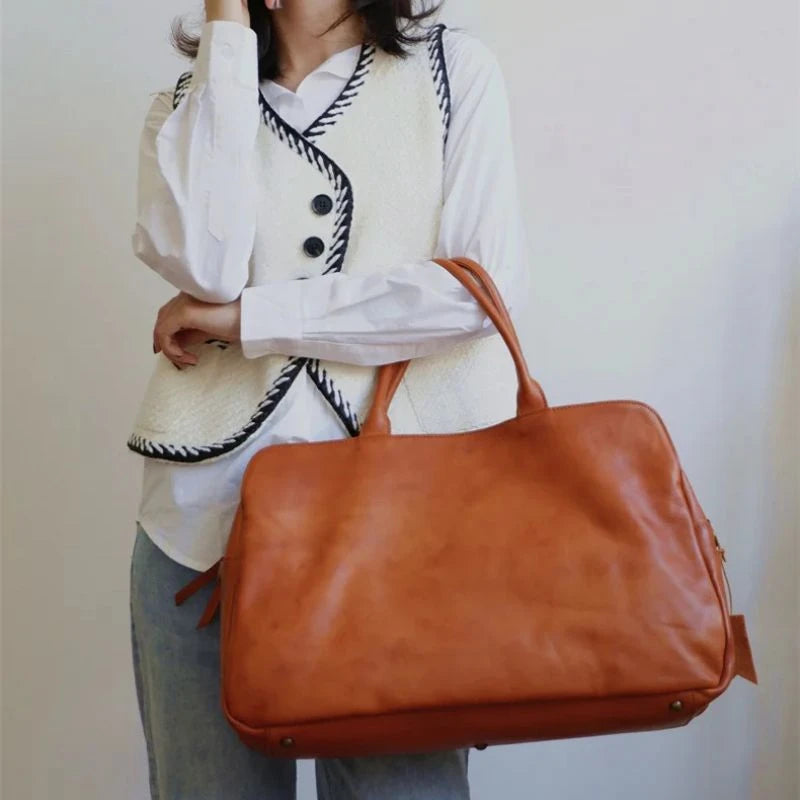 Woman wearing light vest and white shirt holding brow leather bag, stylish and elegant combination.
