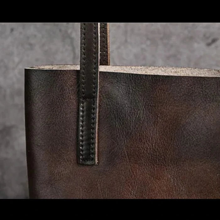close-up view of a brown leather bag highlighting subtle details of texture and stitching.
