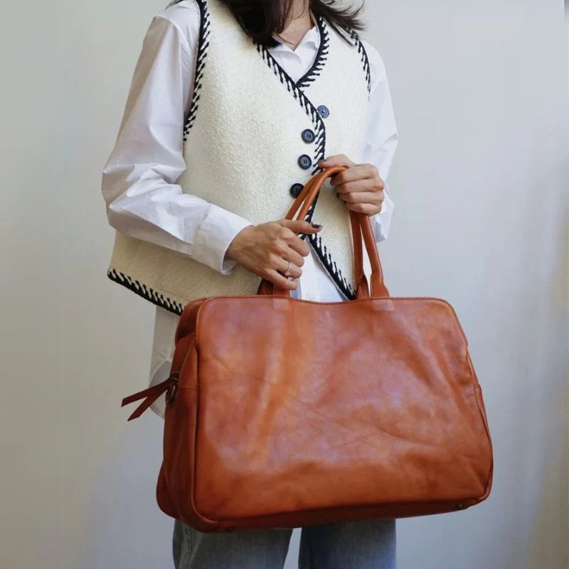 Woman holding an brown leather bag displaying a casual yet elegant style.